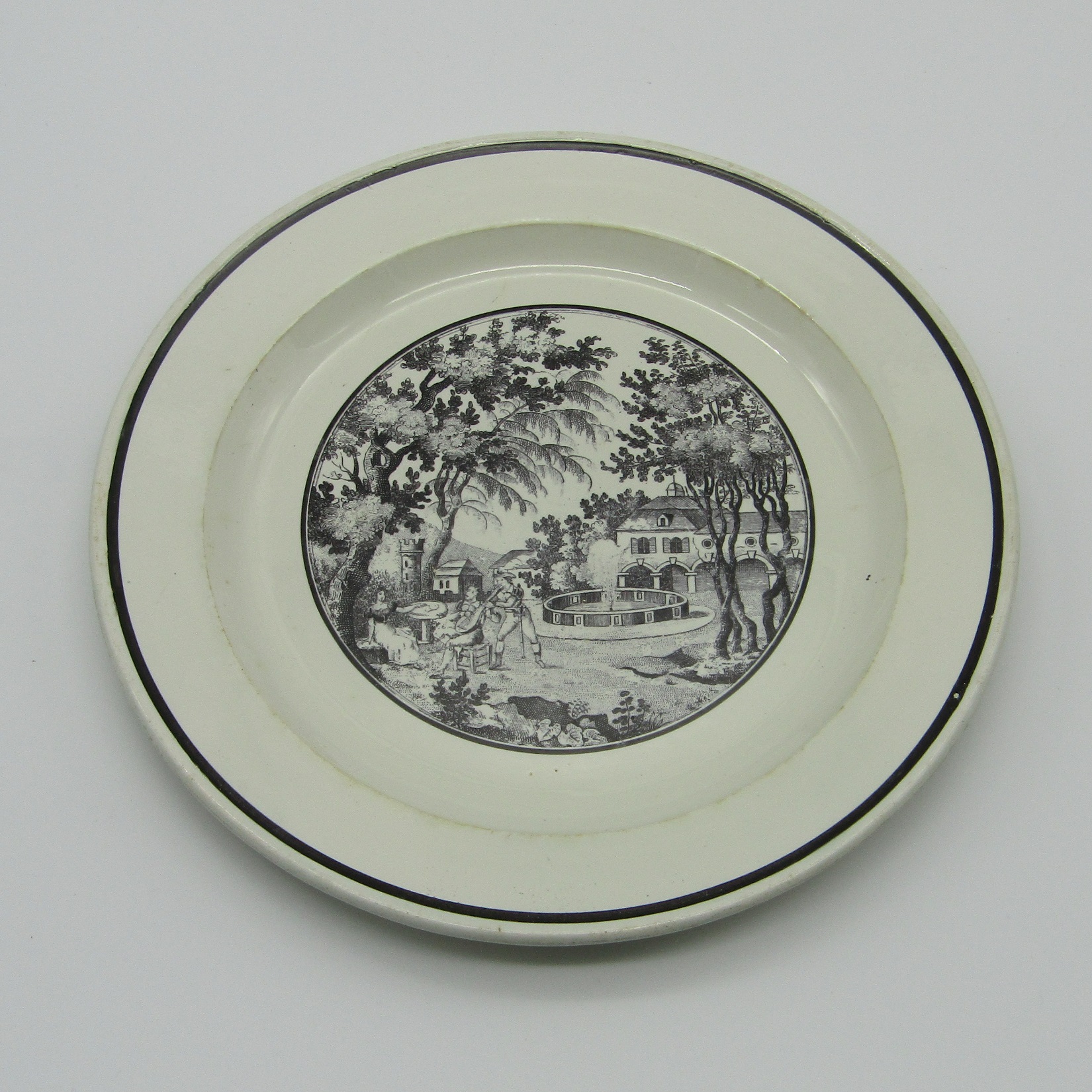 Sarreguemines. Assiette en faïence à décor en grisaille de personnages dans un parc, XIXe siècle