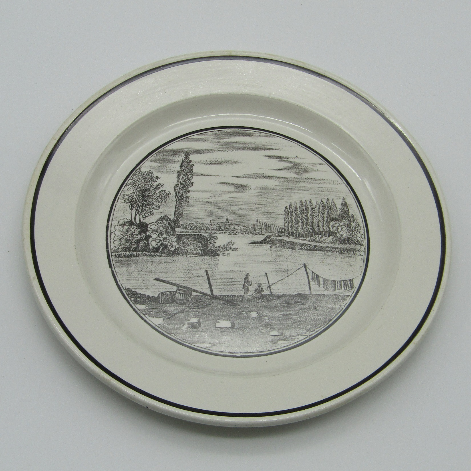 Sarreguemines. Assiette en faïence à décor de personnages au bord d\'une rivière, XIXe siècle
