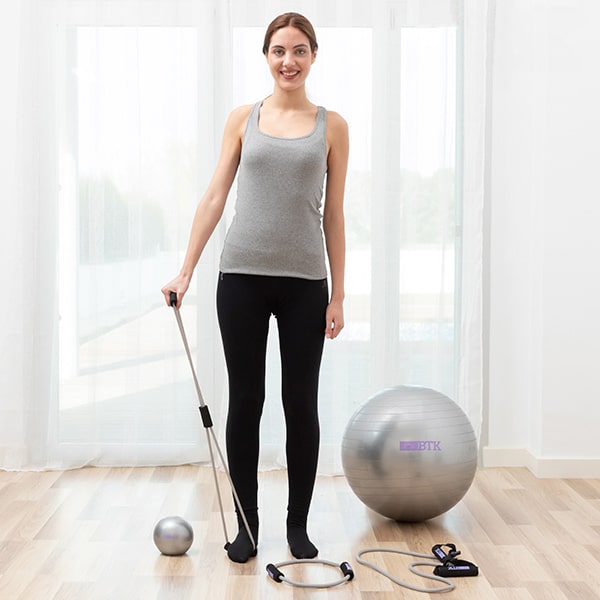 femme faisant des exercices avec un ballon de gym et un élastique de fitness