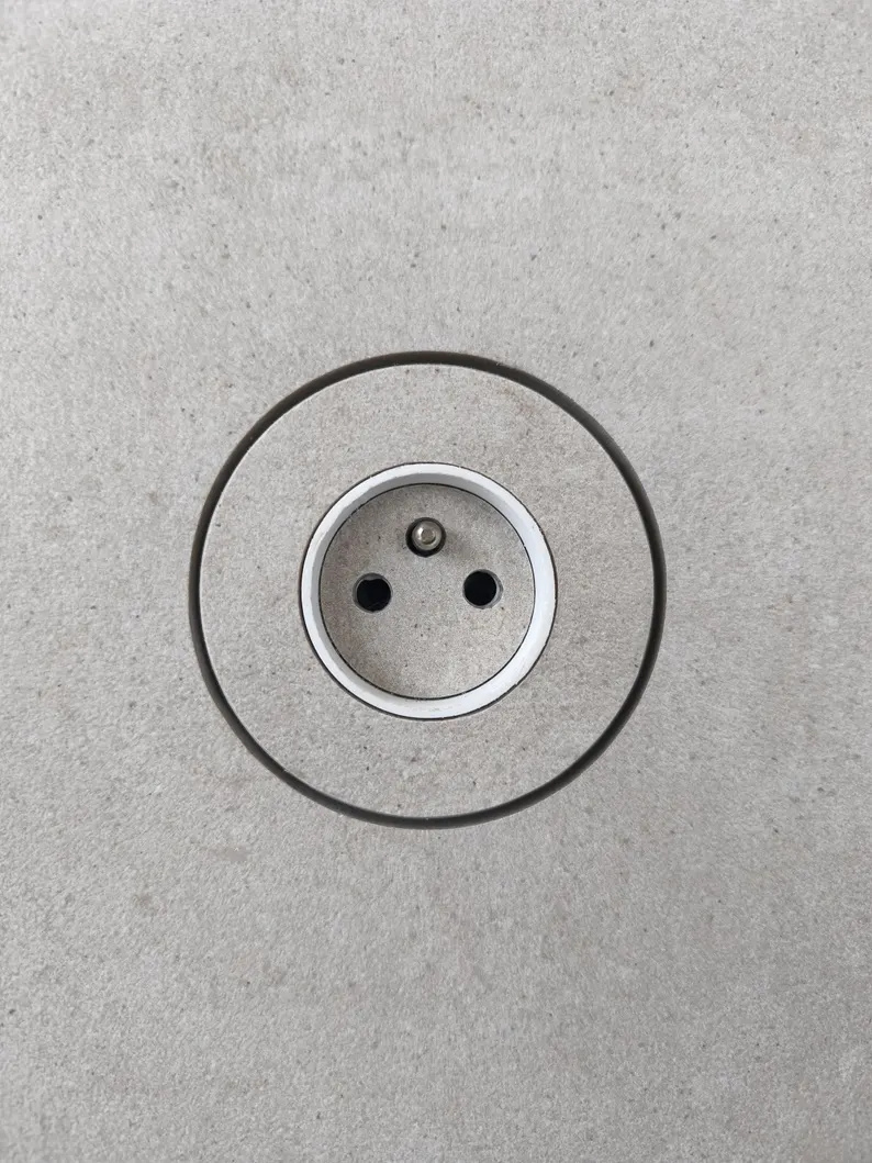 Prise ronde intégrée dans un carrelage gris