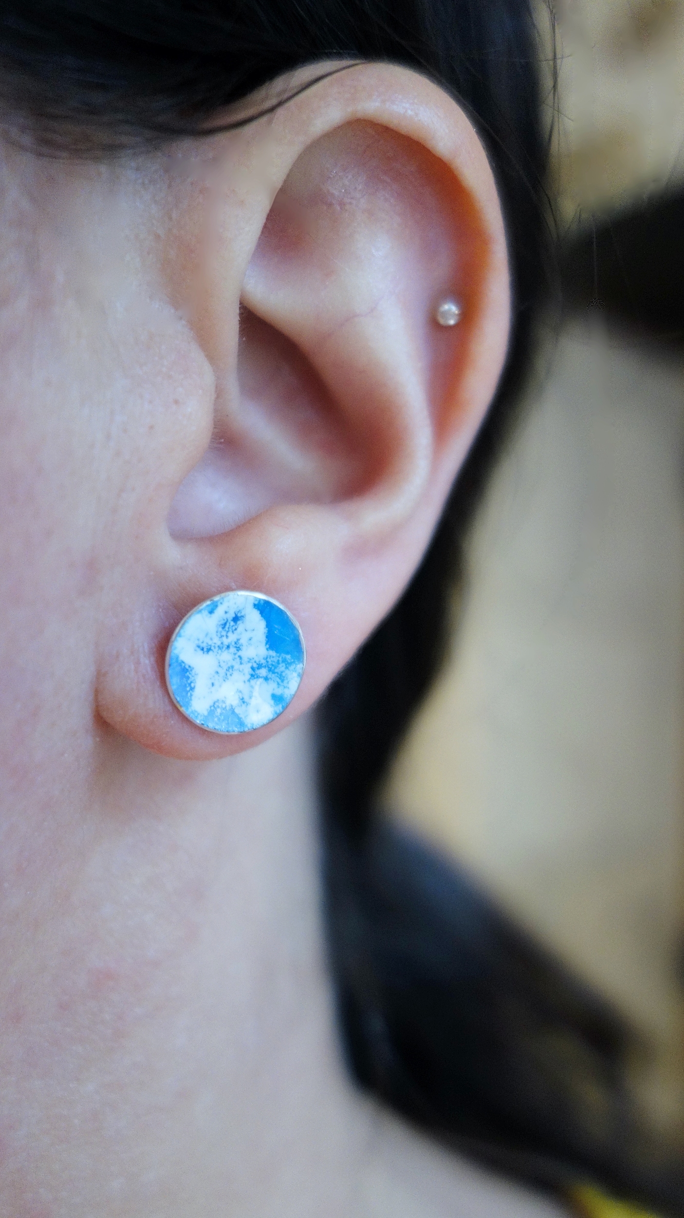 Paire de puces d'oreilles &quot;Floral&quot; avec émail bleu ciel et blanc. photo portée à la lumière du jour