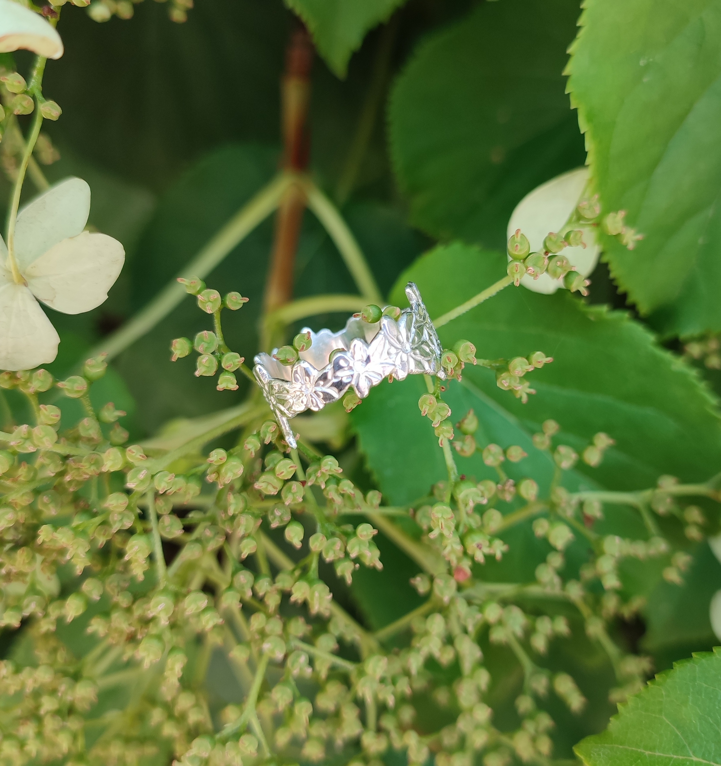 Commande personnalisée bague fleurs en argent massif ciselé, photo en extérieur sur un végétal