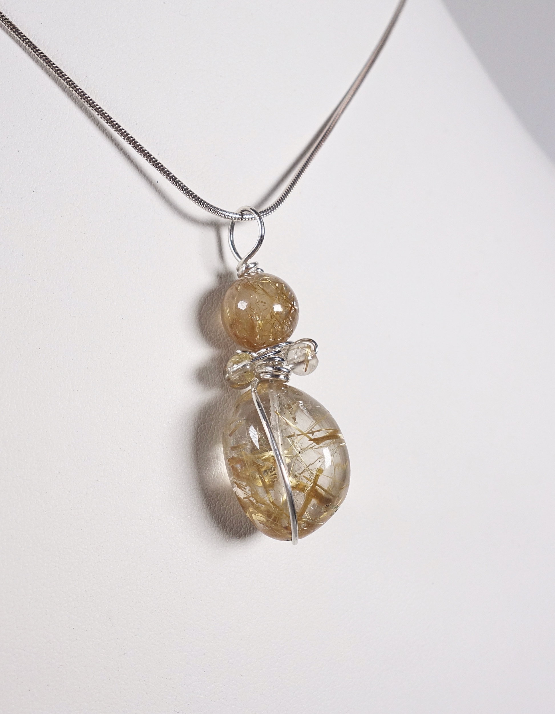 Pendentif &quot;Simplissimes&quot; en argent massif et quartz à rutiles, vue de profil sur buste blanc et fond blanc à la lumière artificielle