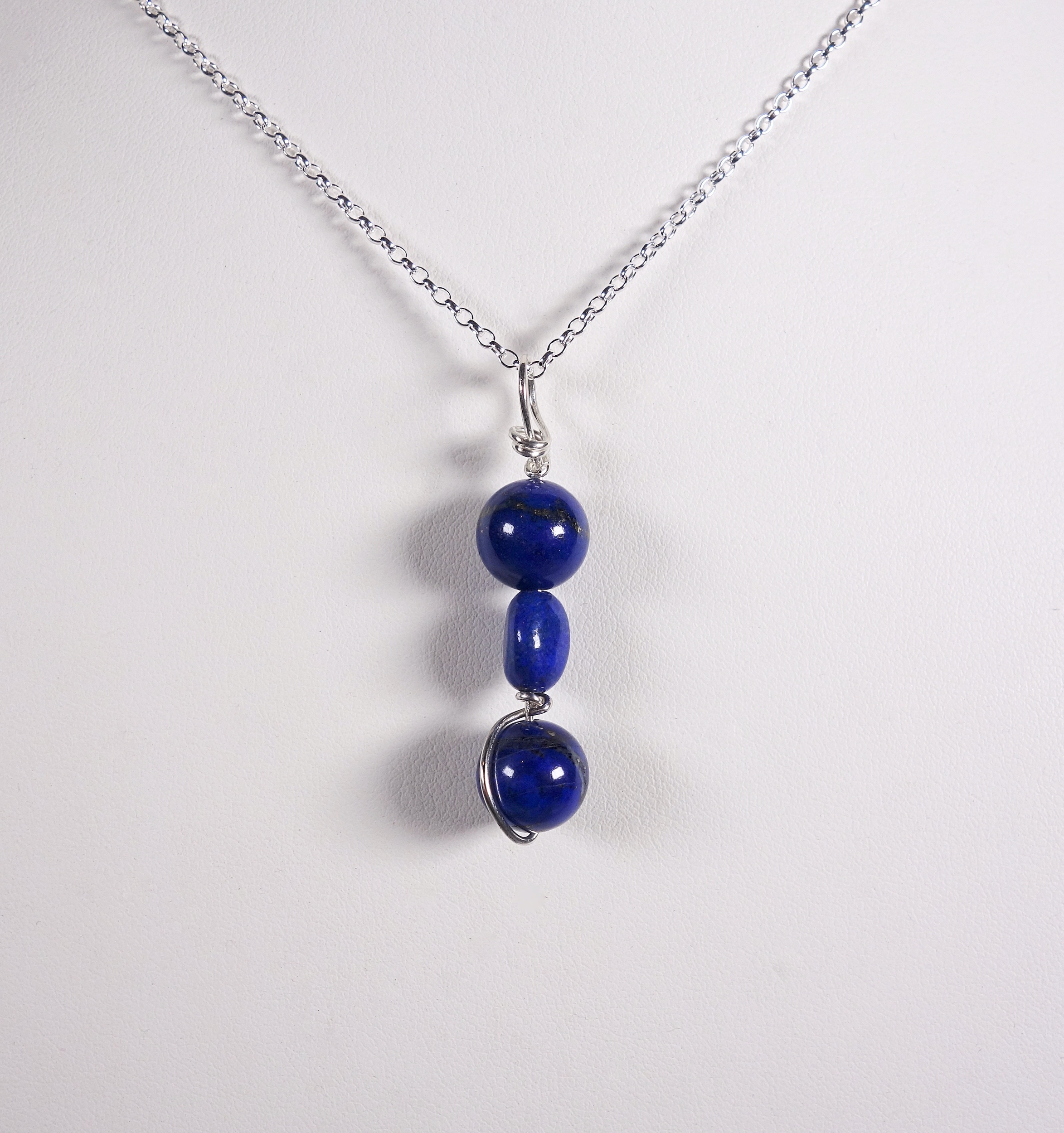 pendentif &quot;simplissimes&quot; en argent massif et lapis lazuli vue de face sur un buste blanc, à la lumière artificielle