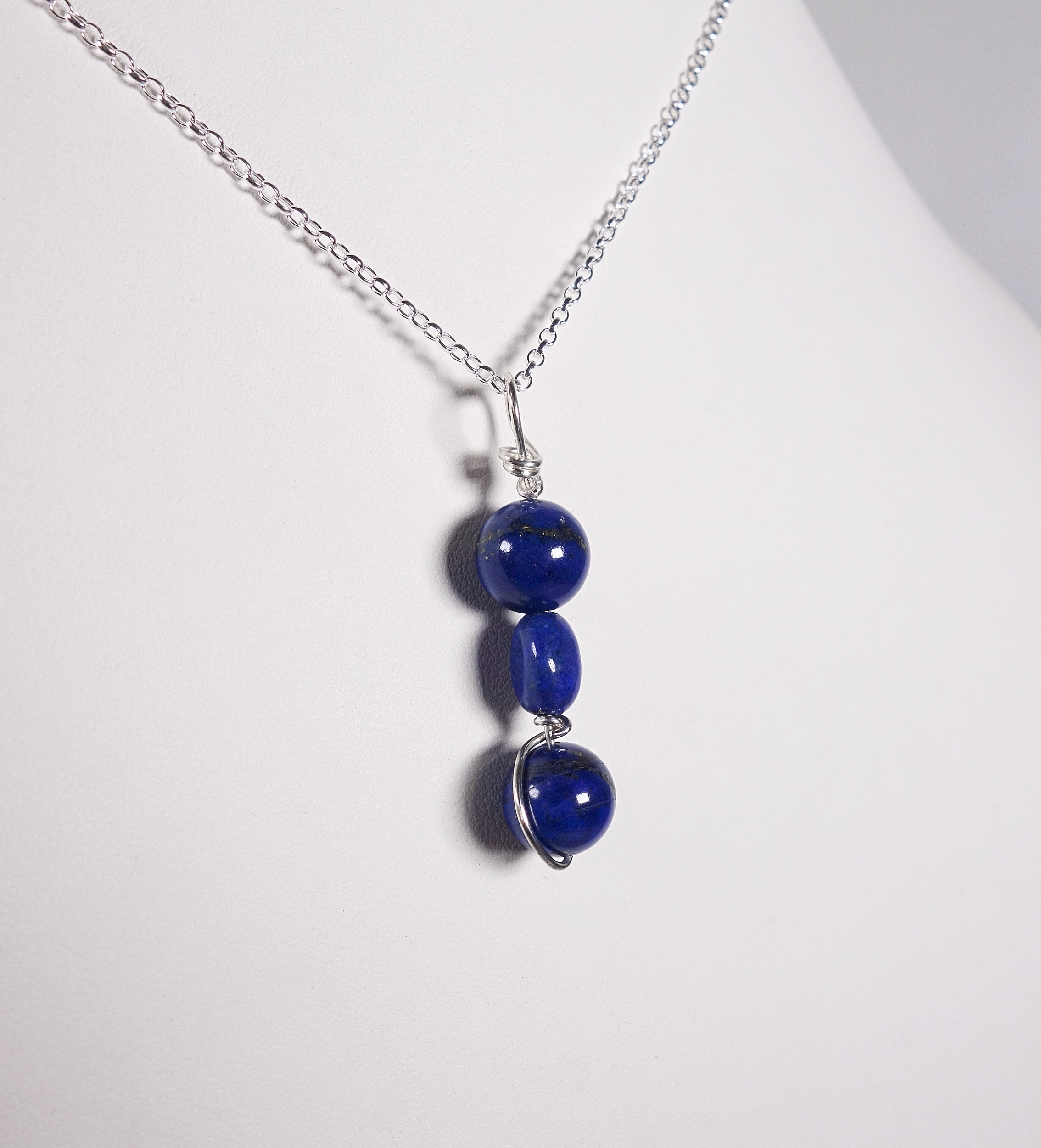 pendentif &quot;simplissimes&quot; en argent massif et lapis lazuli vue de biais sur un buste blanc, à la lumière artificielle