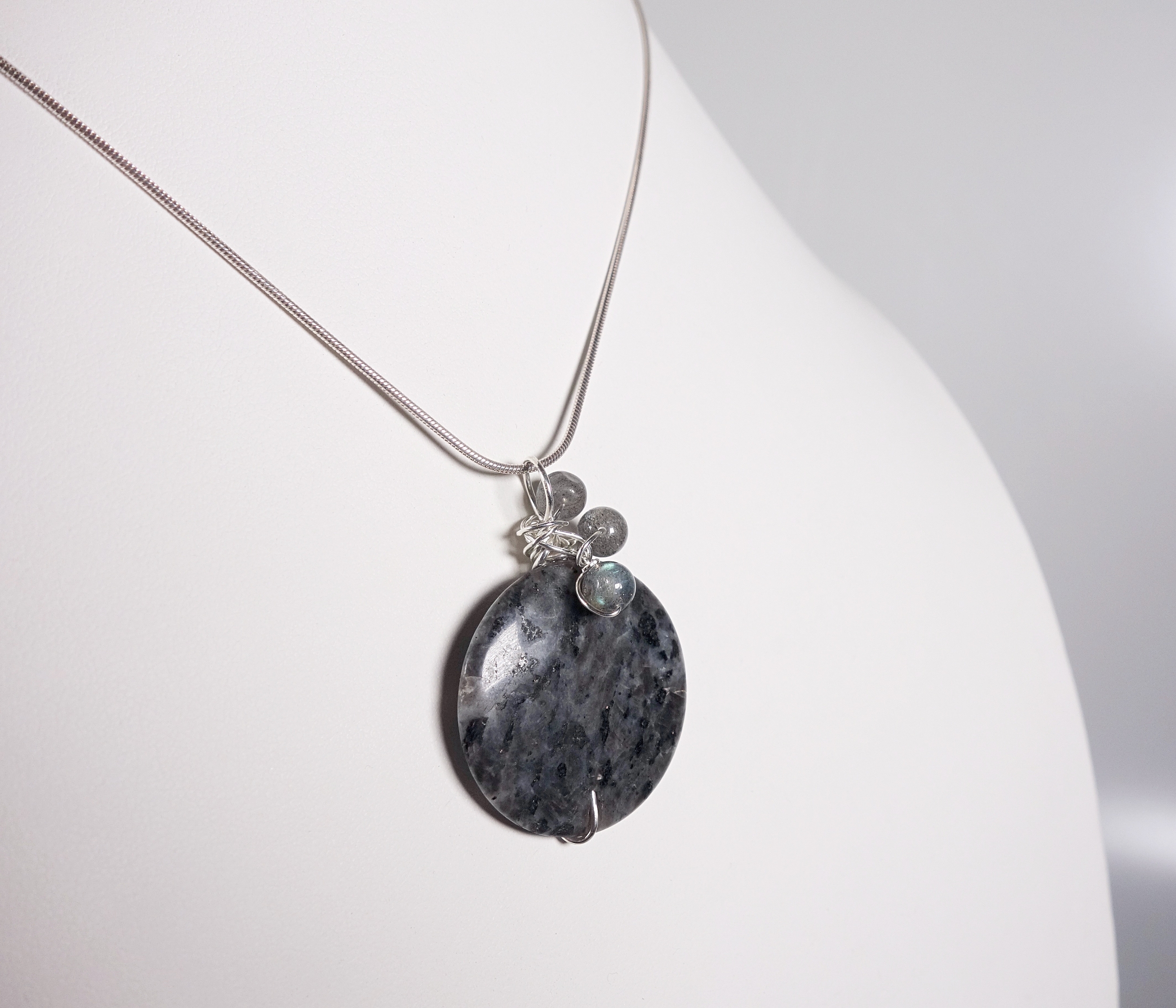 Pendentif &quot;Simplissimes&quot; en argent massif avec des perles en labradorite, vue de profil, sur un buste blanc, à la lumière artificielle