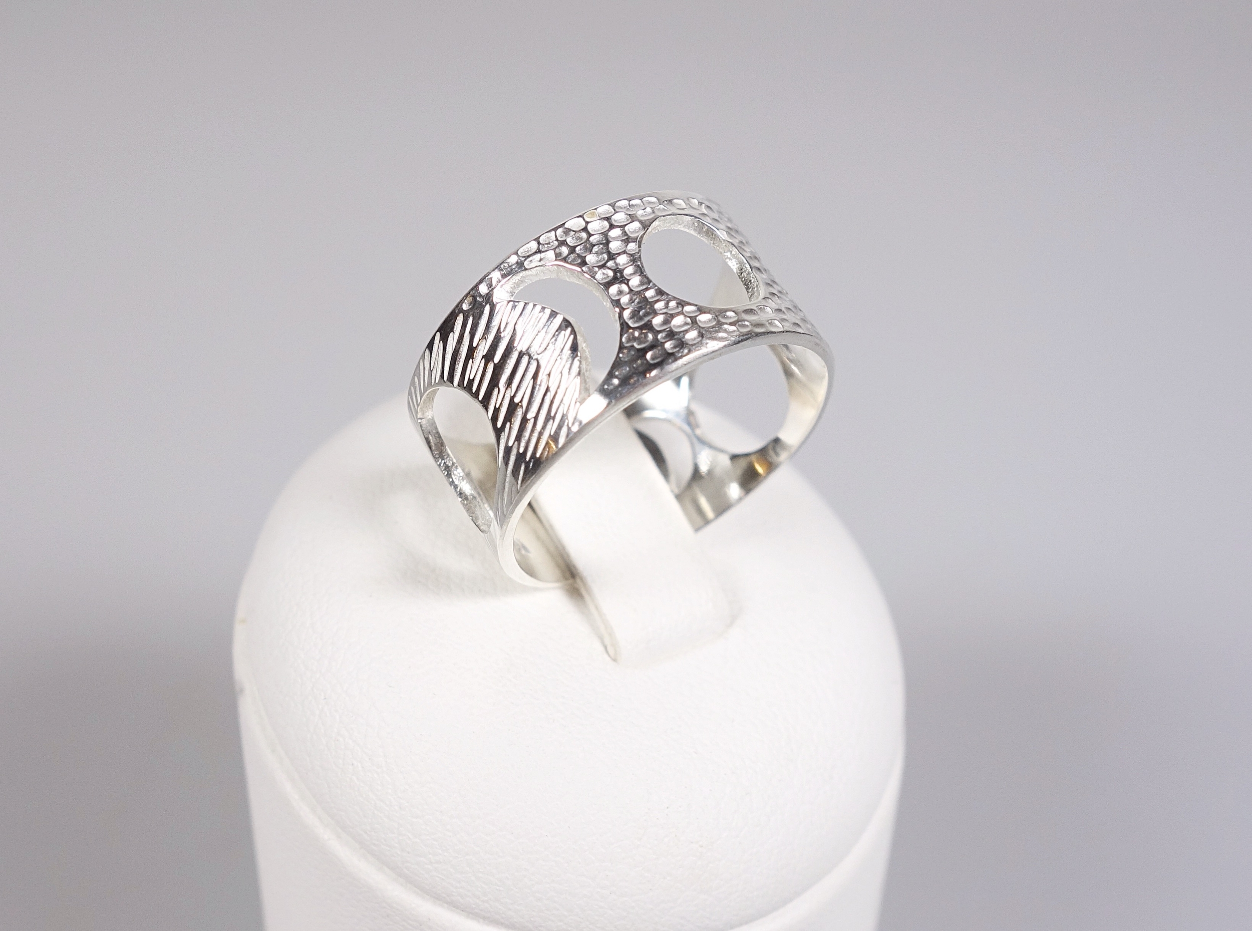 Bague féminin sacré (cycle lunaire) en argent massif ciselé, vue de profil sur présentoir blanc et fond blanc à la lumière électrique