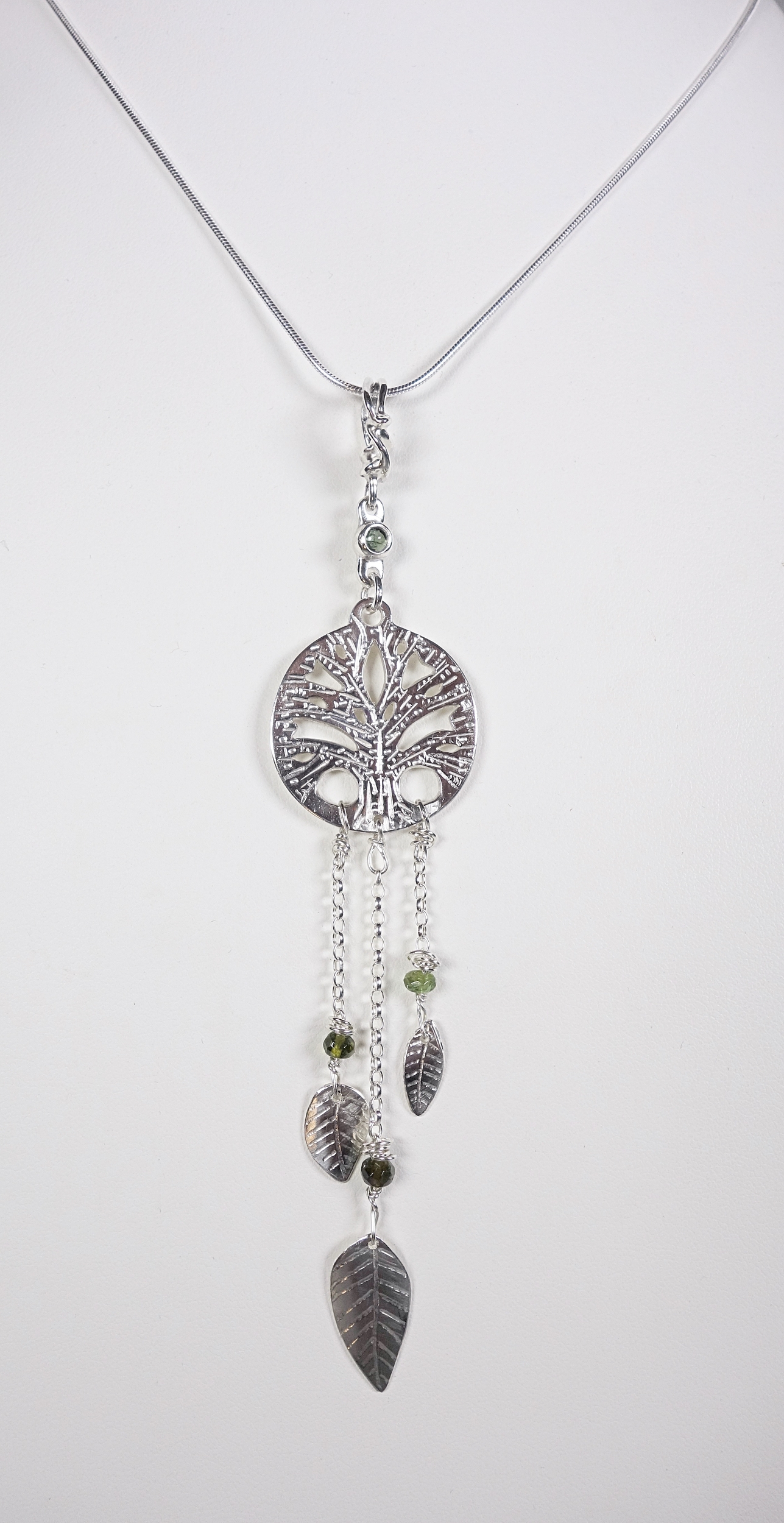 Arbre de vie. Pendentif. Bijou nature. Talisman. Argent massif ciselé et tourmaline. Vert. Fait main. Photo de face sur buste blanc. Pétale dargent.