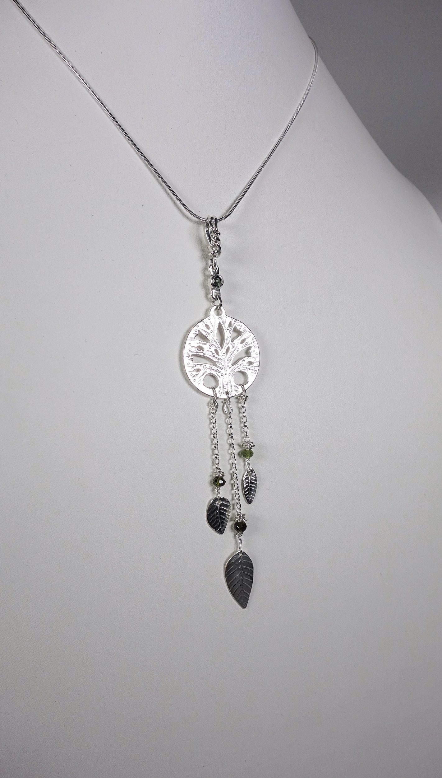Arbre de vie. Pendentif. Bijou nature. Talisman. Argent massif ciselé et tourmaline. Vert. Fait main. Photo de face sur buste blanc. Pétale dargent.