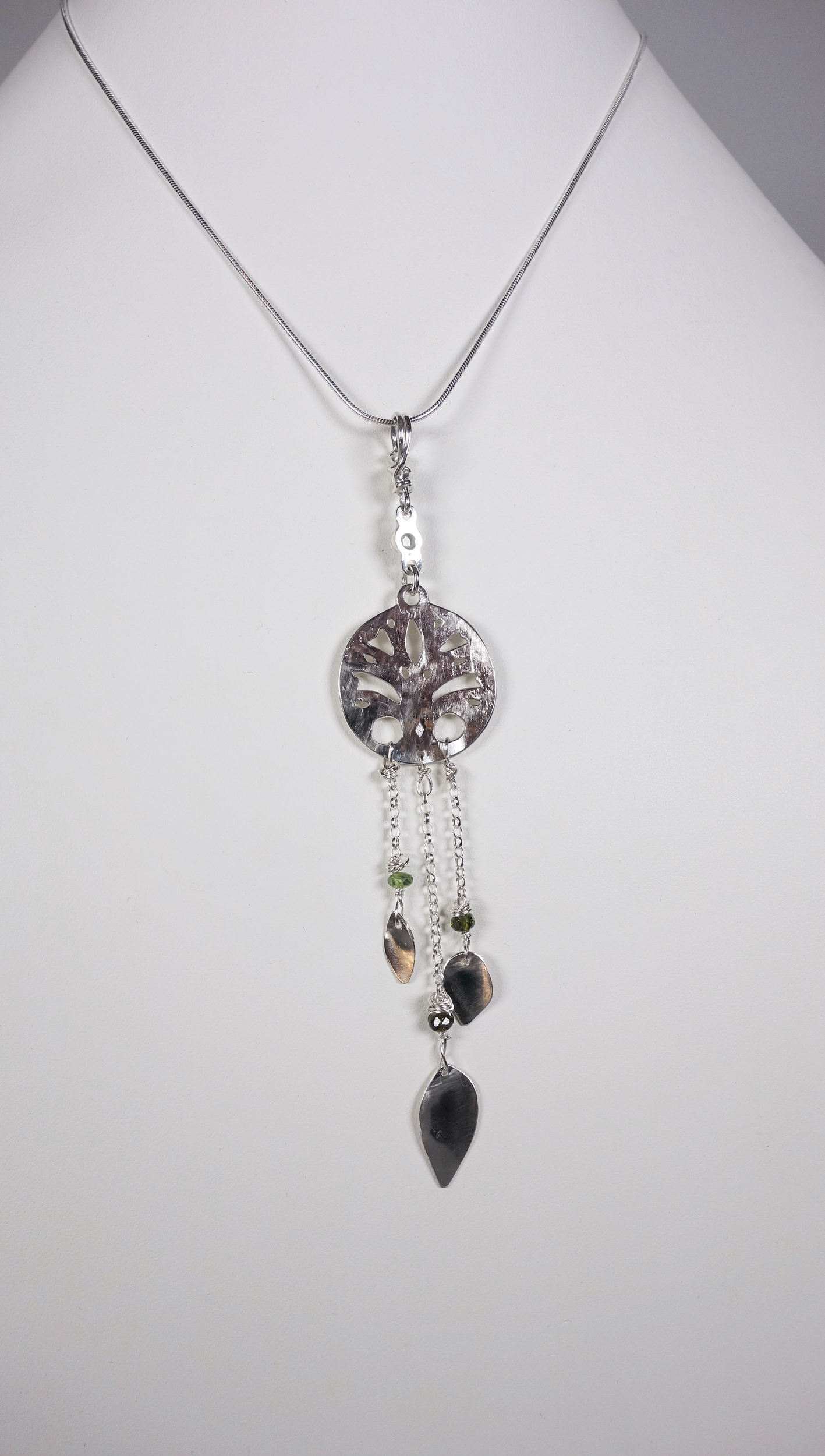 Arbre de vie. Pendentif. Bijou nature. Talisman. Argent massif ciselé et tourmaline. Vert. Fait main. Photo de dos sur buste blanc. Pétale dargent.