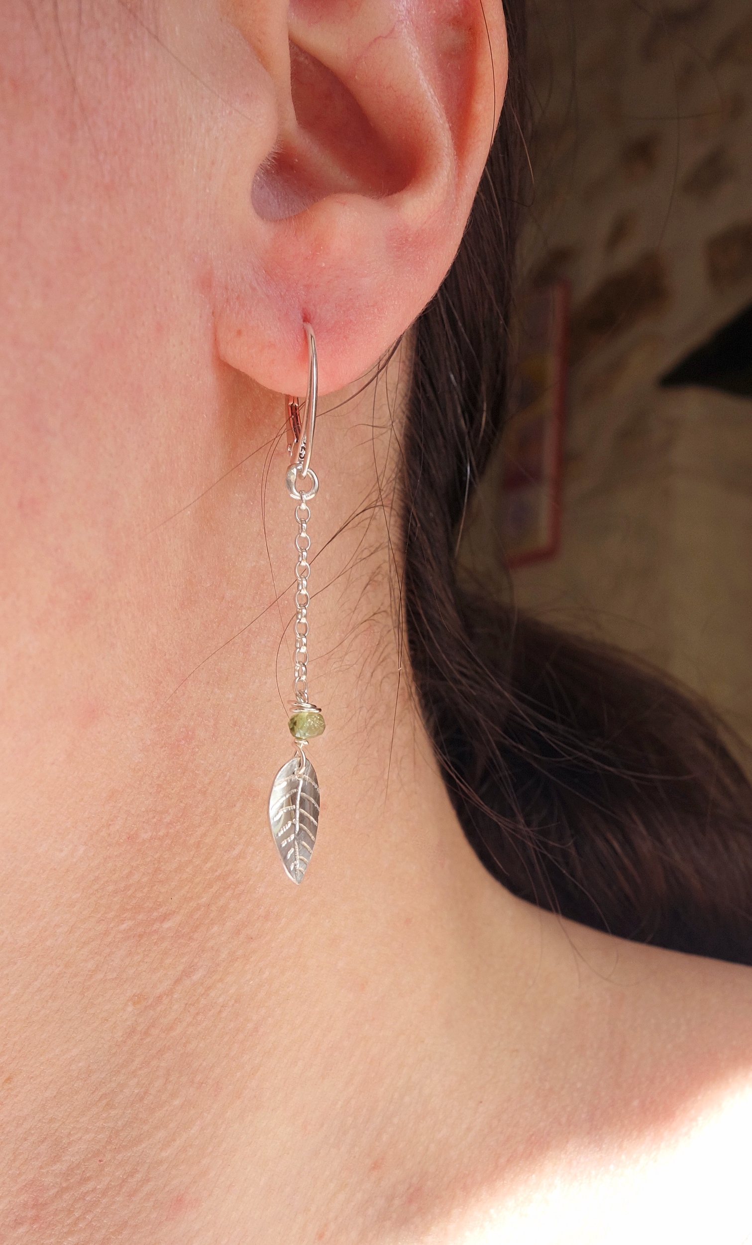 Boucles d'oreilles pendantes nature en argent massif avec feuille et tourmaline, vue portée à la lumière naturelle