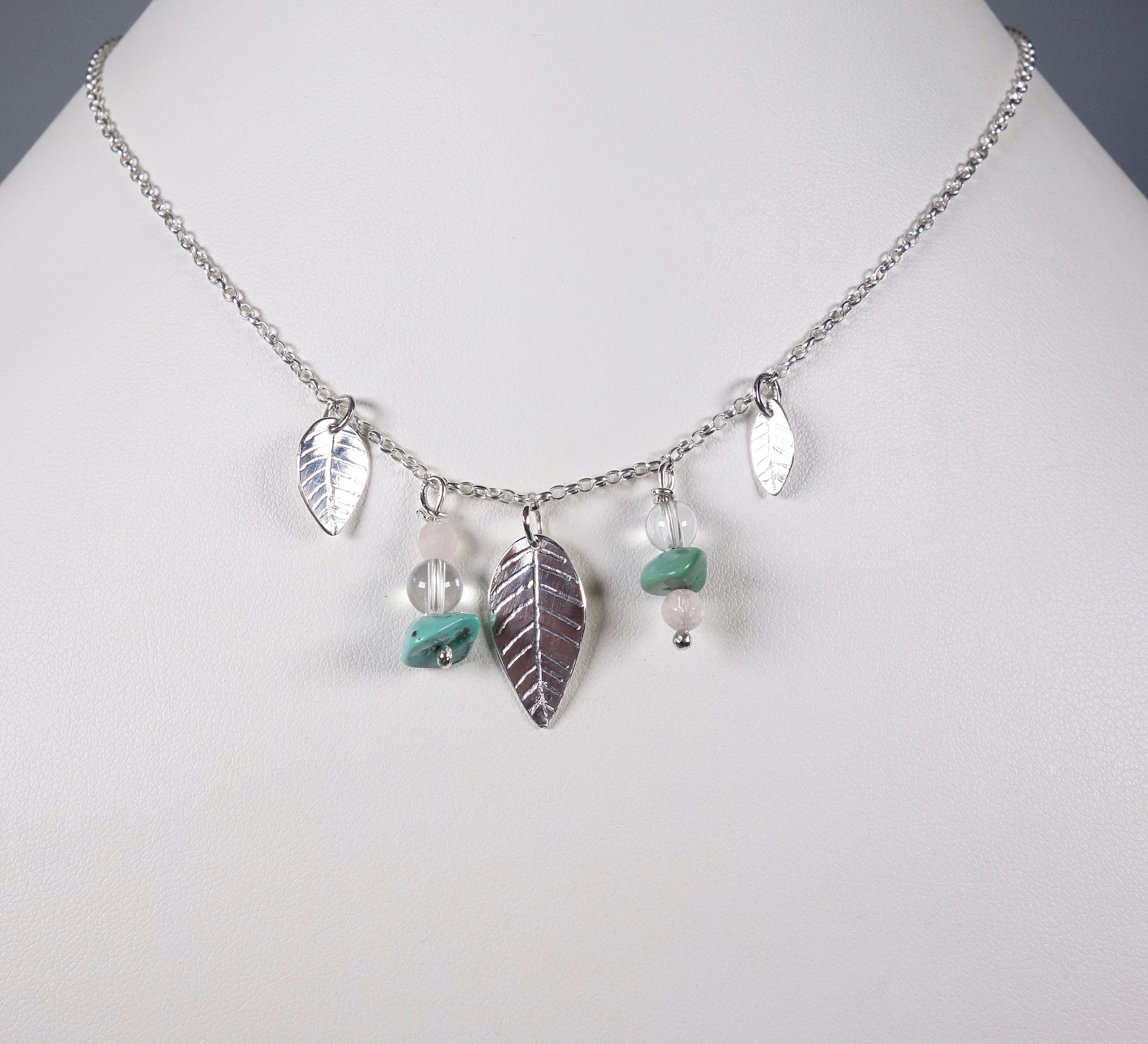 Collier ethnique en argent massif avec feuilles et perles de turquoise, quartz rose et cristal de roche., vue de face sur fond blanc. Création Pétale dargent