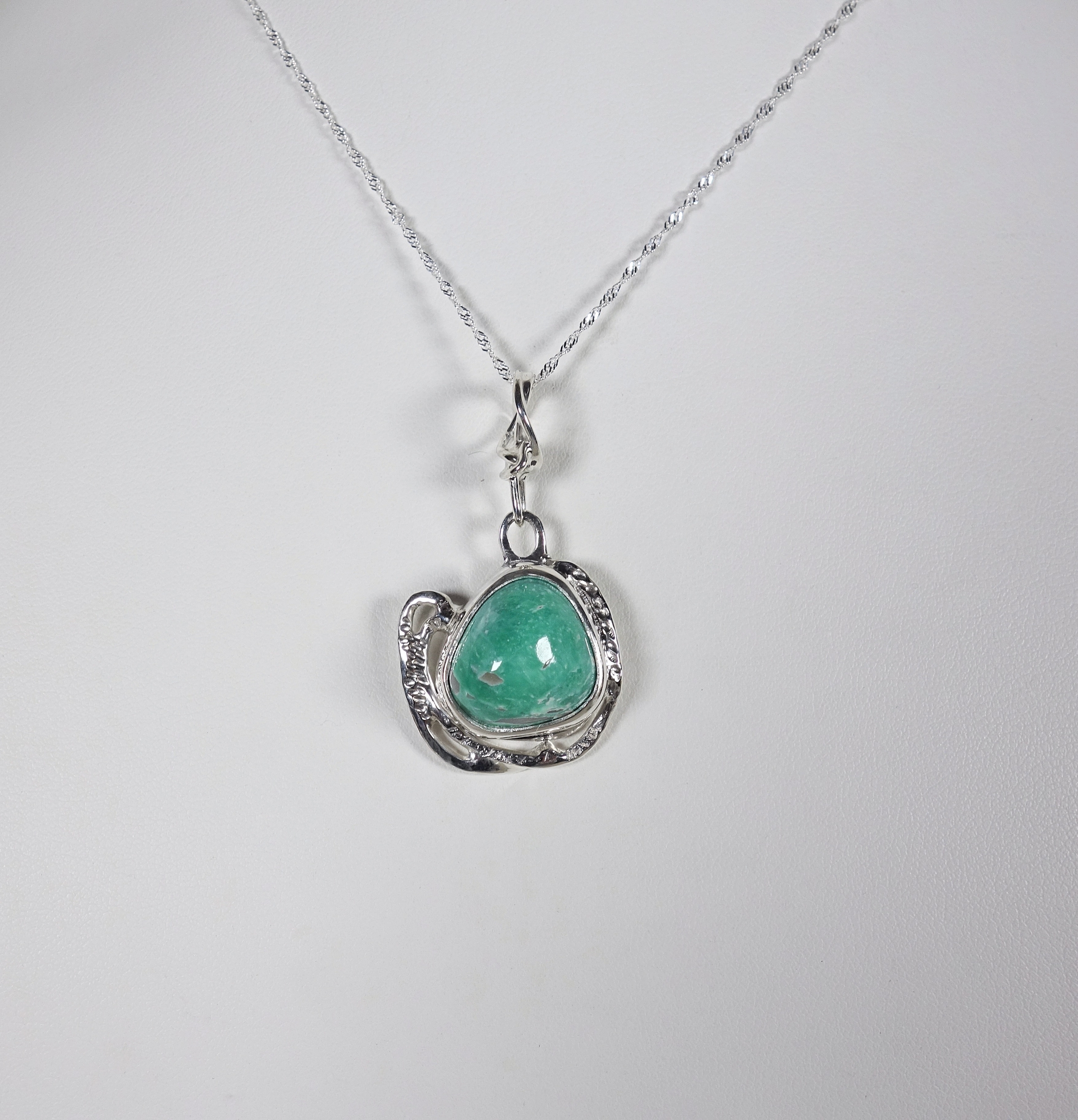 Pendentif en argent massif et turquoise vu de face sur fond blanc. Pétale dargent
