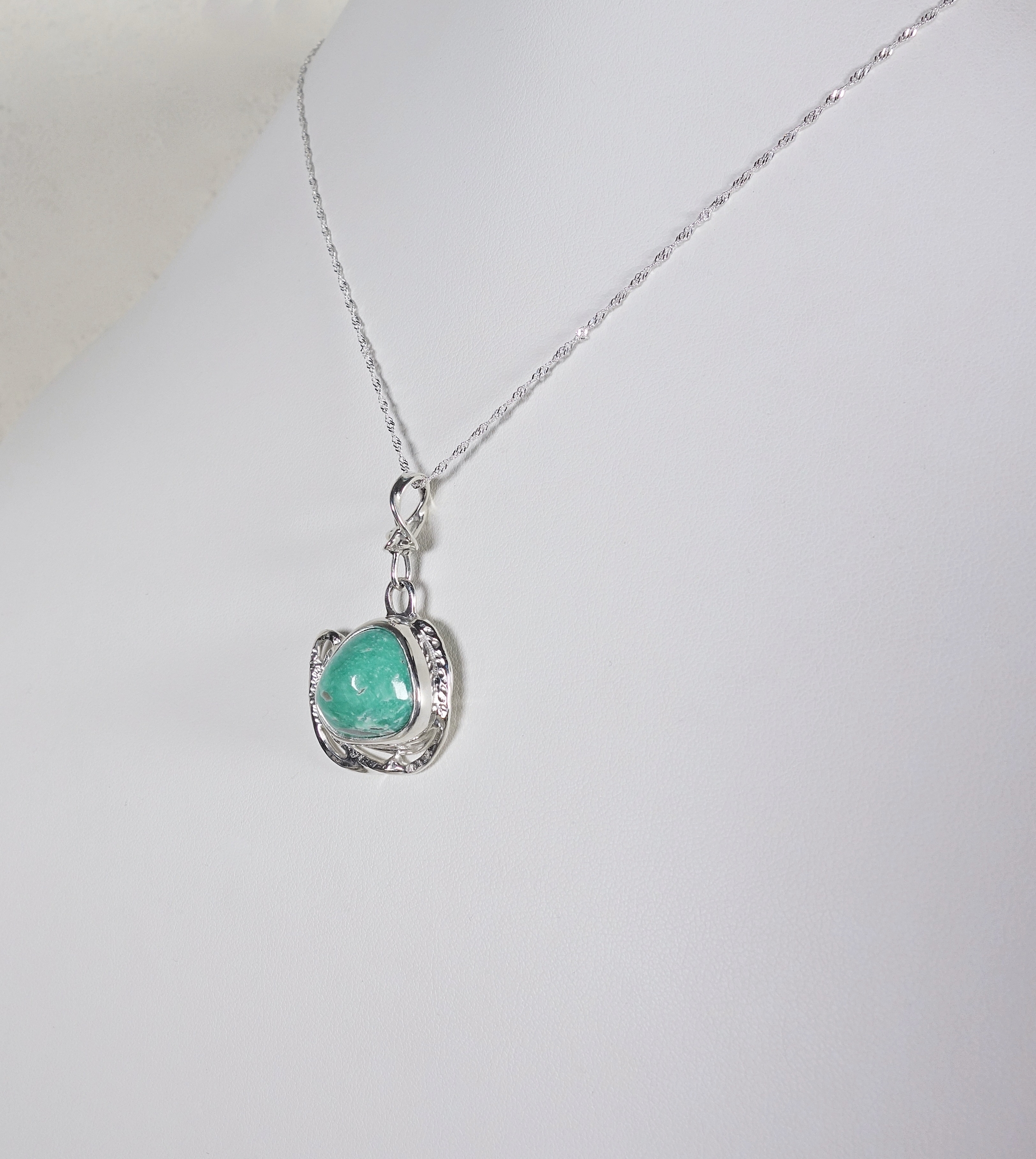 Pendentif en argent et turquoise vu de profil sur fond blanc. Pétale dargent
