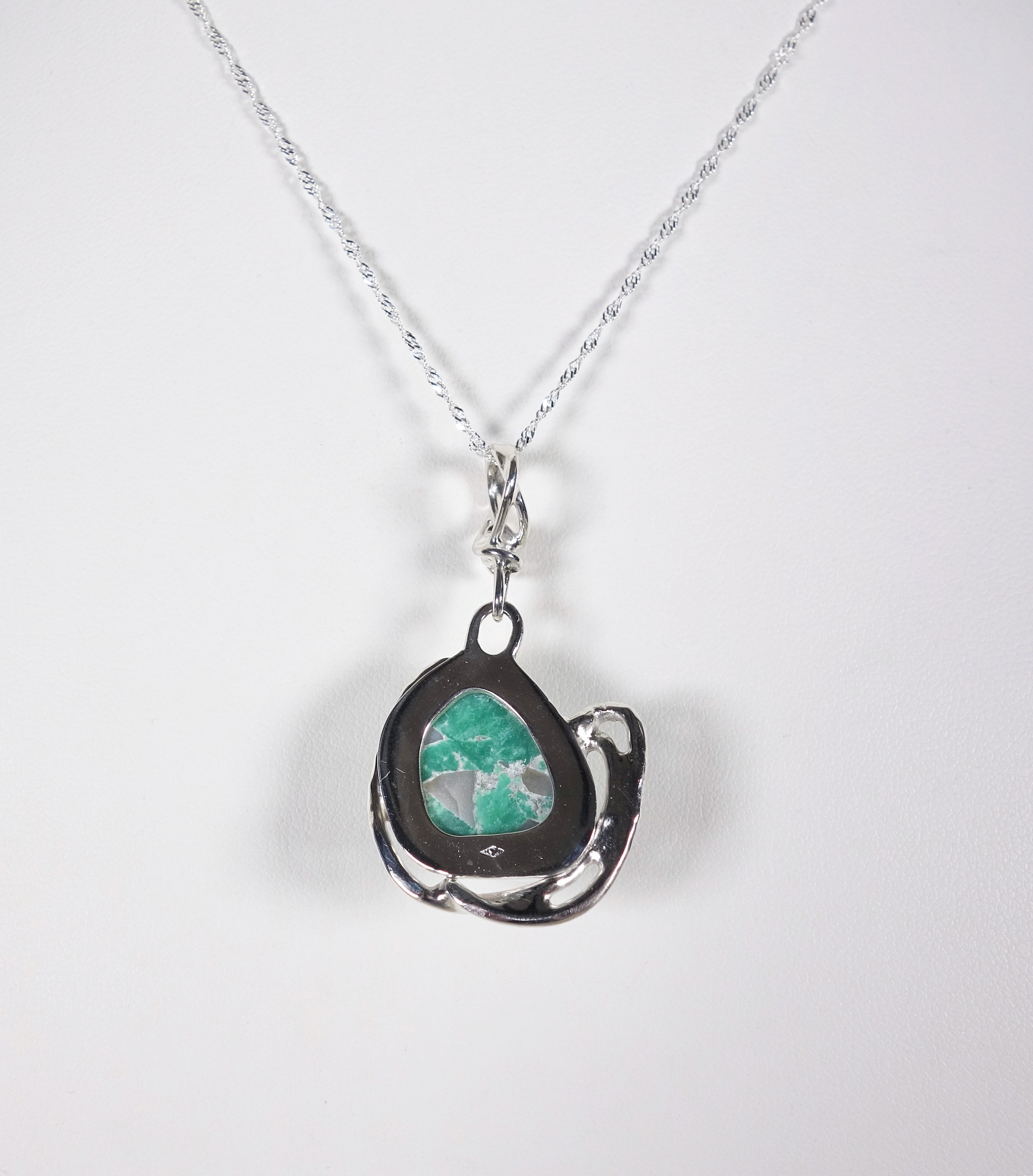 Pendentif en argent et turquoise vu de dos sur fond blanc. Pétale dargent