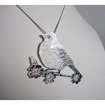 Pendentif oiseau Madame M en argent massif et péristérite, vue de profil sur buste blanc, à la lumière artificielle