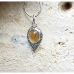 Pendentif personnalisé Mme R en argent et citrine, vue de face contre un mur à la lumière du jour