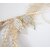 Boucles d'oreilles Ailes d'Ange en argent massif ciselé, vue de profil, sur fond blanc et graminées, à la lumière artificielle