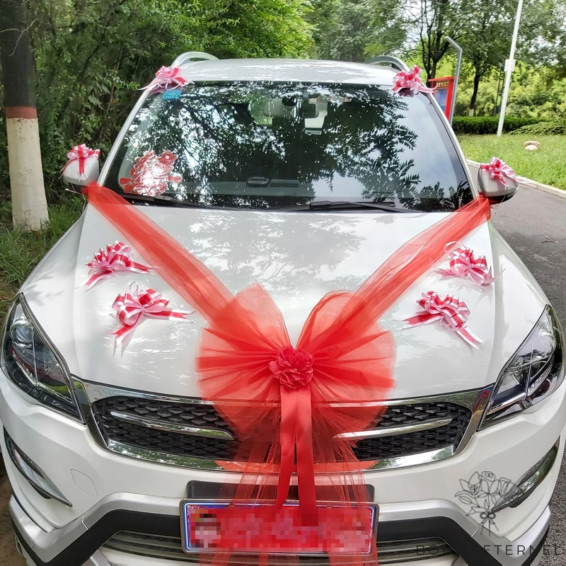 Décoration de voiture avec un nœud rose clair et des détails floraux pour des invités de mariage