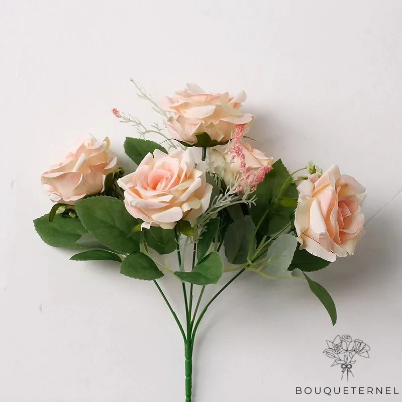 Bouquet de roses artificielles dans des teintes de pêche et de crème, arrangé contre un fond blanc épuré
