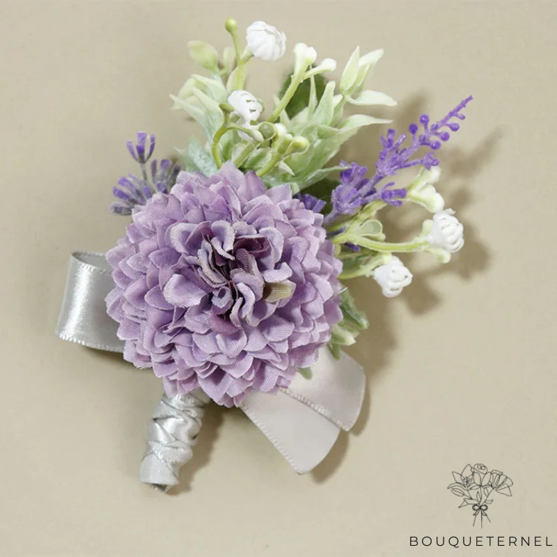 Boutonnière fleur mariage violette avec une grande fleur lavande, petites fleurs blanches et détails verts, ruban argenté