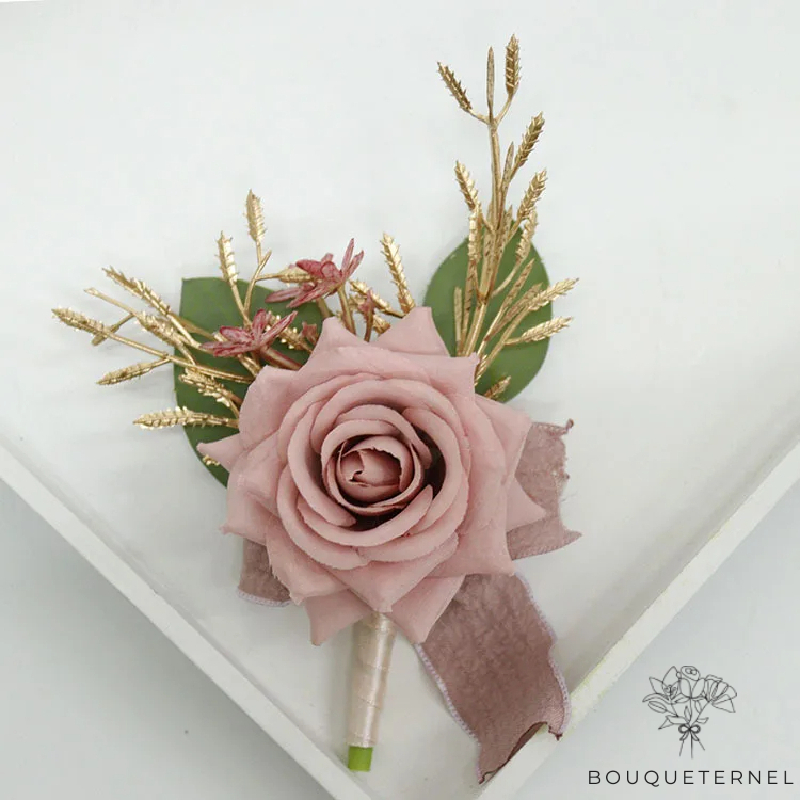 Composition florale pour mariage, boutonnière rose pâle avec ruban et éléments dorés