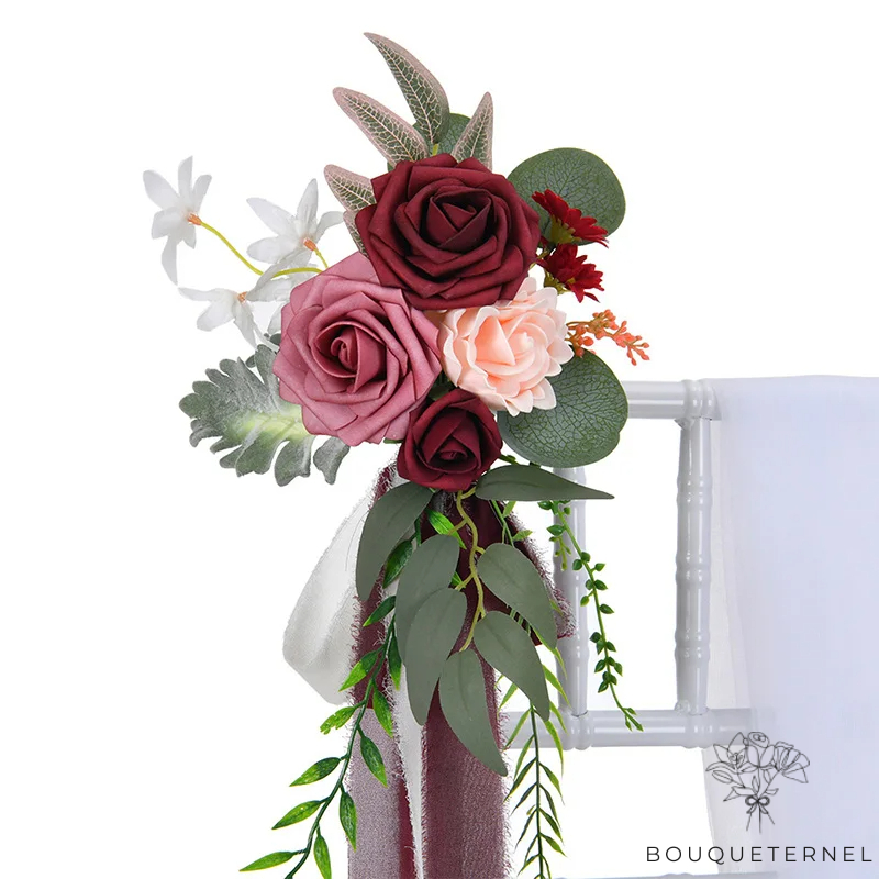 Décoration florale pour chaise de mariage bohème avec des roses bordeaux et roses, accompagnées de feuillages et d'une écharpe blanche