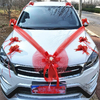 Voiture décorée d'un grand nœud rouge et de fleurs pour un style chic lors d'un mariage