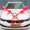 Décoration voiture de mariage en rouge et blanc, avec des fleurs artificielles rouges et blanches disposées en cœur sur le capot