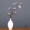Branche artificielle à fleurs blanches dressée dans un vase blanc élancé, sur un fond gris, idéale pour la décoration intérieure