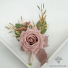 Composition florale pour mariage, boutonnière rose pâle avec ruban et éléments dorés