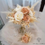 Bouquet de fleurs artificielles pour mariage, composé de roses blanches et beiges avec de petites fleurs crème et des ornements vaporeux