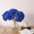 Fleurs Artificielles d'Hortensia Bleu Marine dans un vase transparent, accompagnées d'un pichet blanc et d'un livre sur une table en bois clair