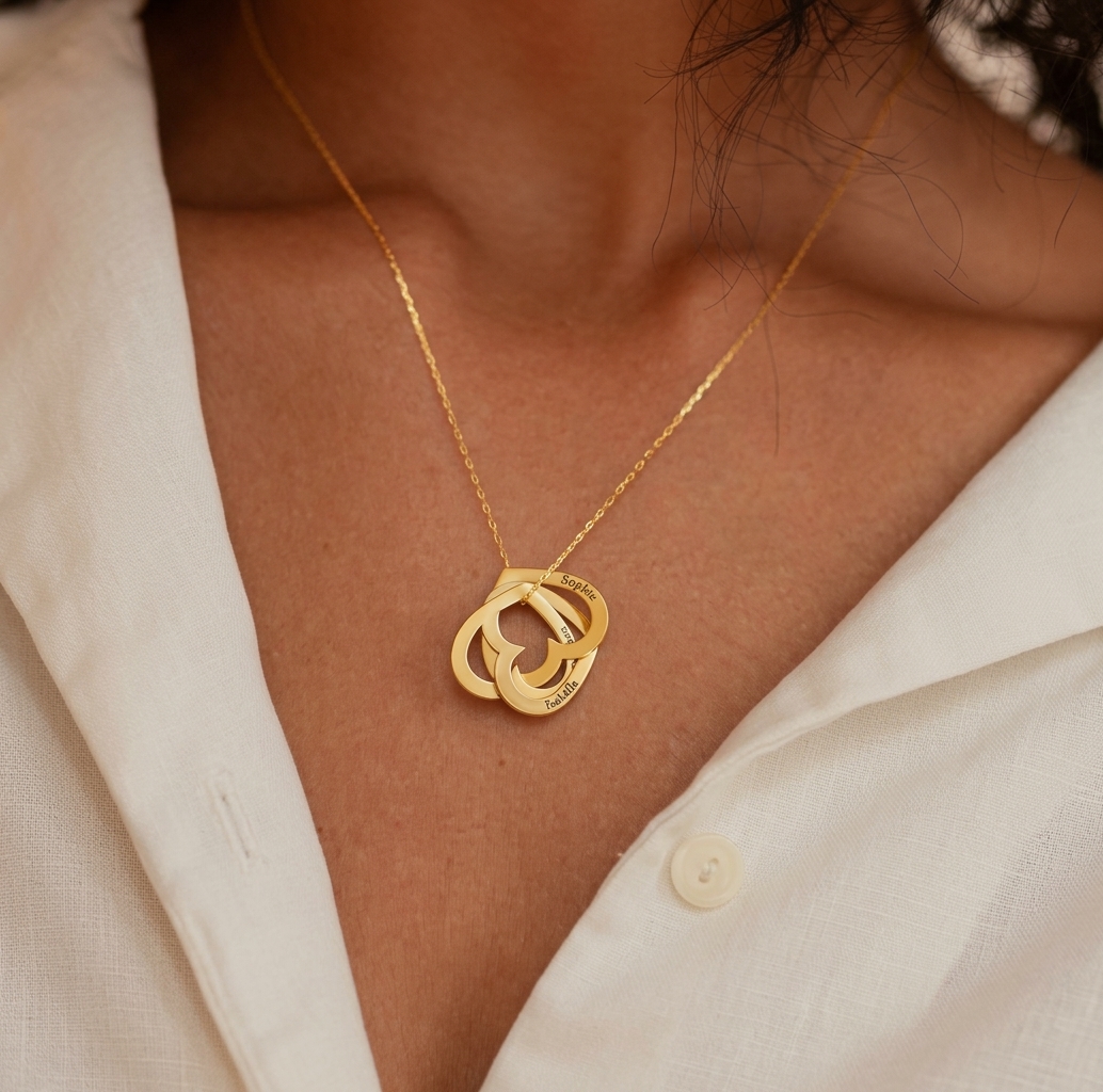 Femme portant un collier prénoms cœurs enlacés doré, prénoms gravés sur les cœurs
