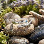 Bague prénom argent 925 gravée de 2 prénoms posée sur des galets