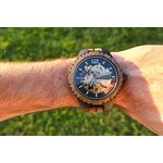 Montre en bois automatique portée au poignet, mouvement mécanique visible