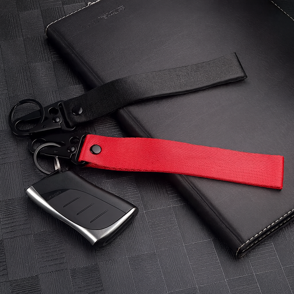 Porte-clés en tissu noir et rouge avec mousqueton, sans logo, posé sur fond texturé