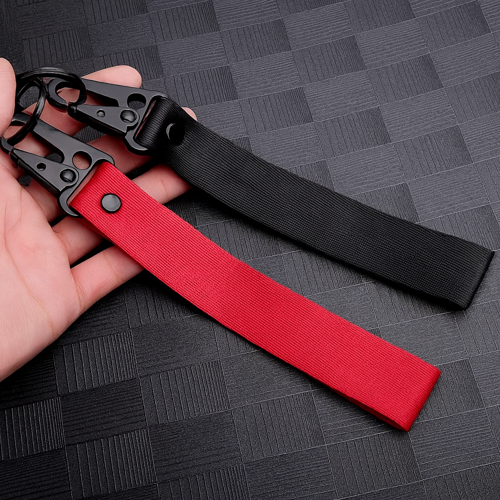 Deux porte-clés en tissu noir et rouge avec mousqueton, présentés dans une main