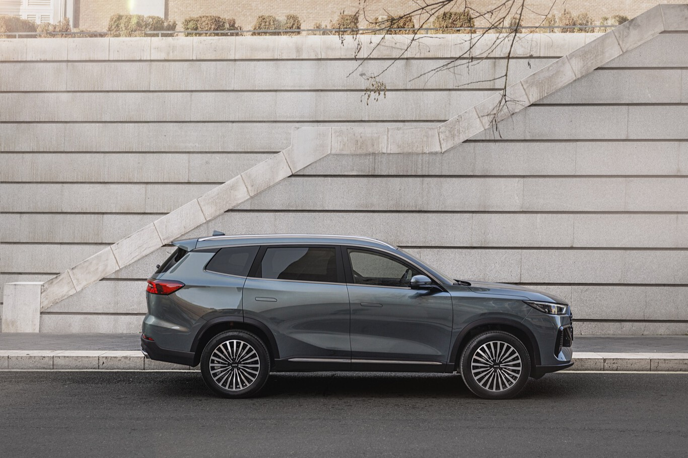 Profil d’un grand SUV urbain stationné devant un mur architectural en béton