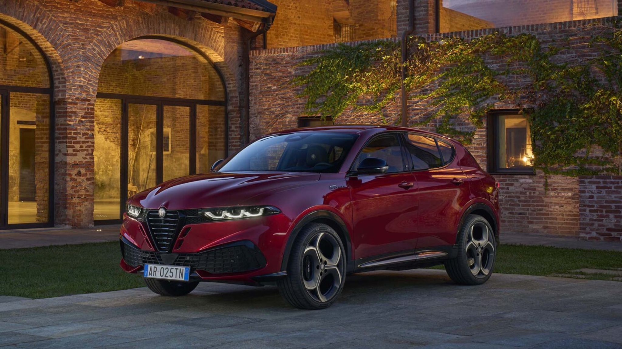 Alfa Romeo Tonale rouge restylé devant une maison en pierre