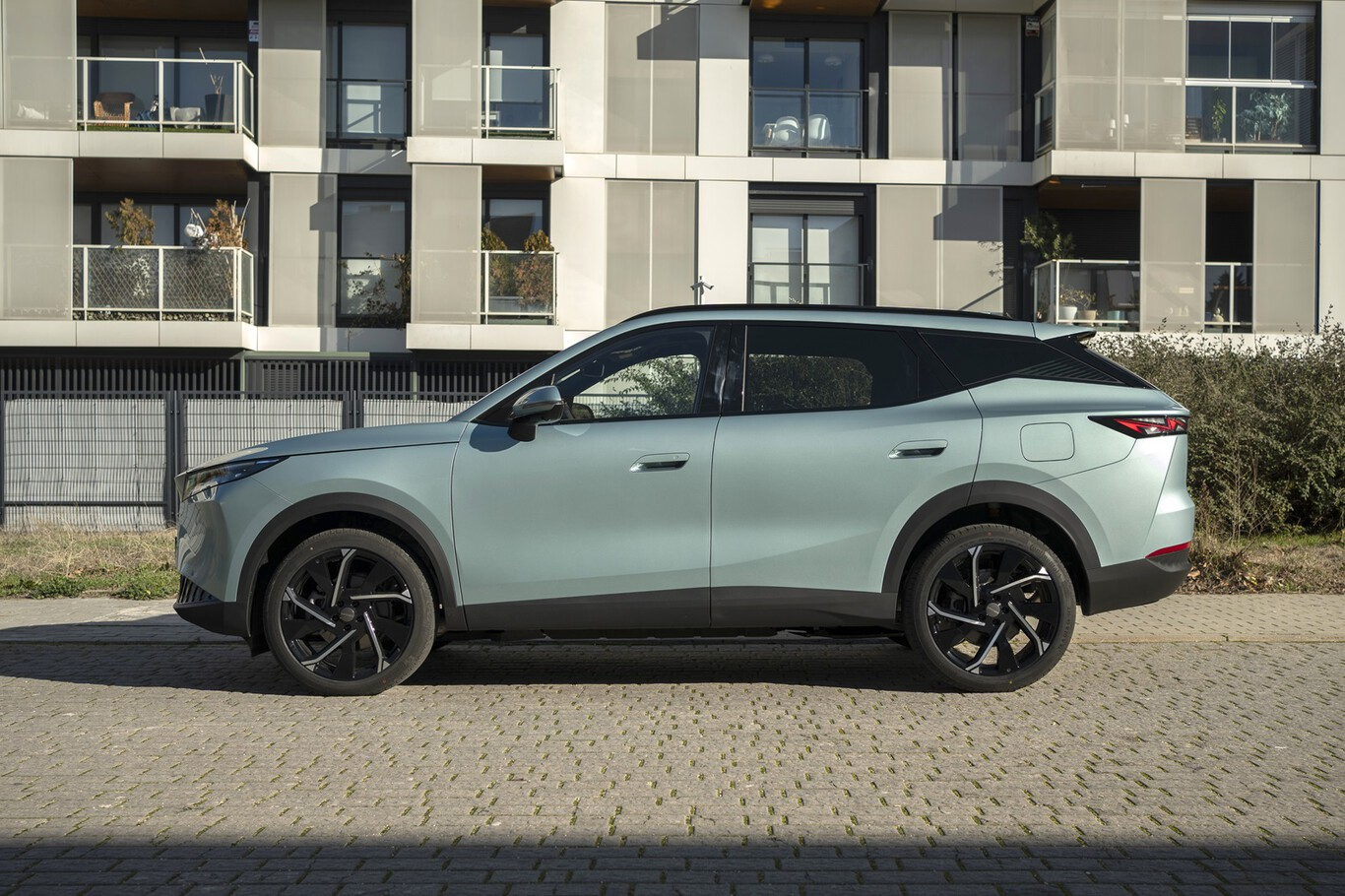 Omoda 7 SHS bleu clair de profil devant des immeubles