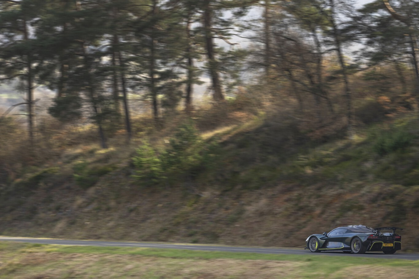 Aston Martin Valhalla roulant au loin sur route boisée