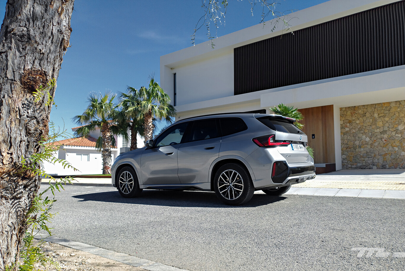 BMW iX1 gris vu de l’arrière devant une villa contemporaine