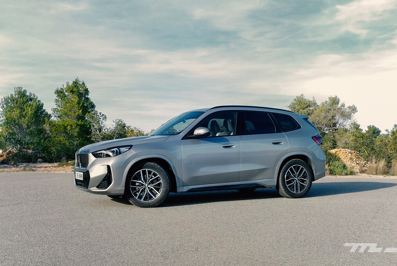BMW iX1 eDrive20 électrique gris en vue de profil sur route dégagée