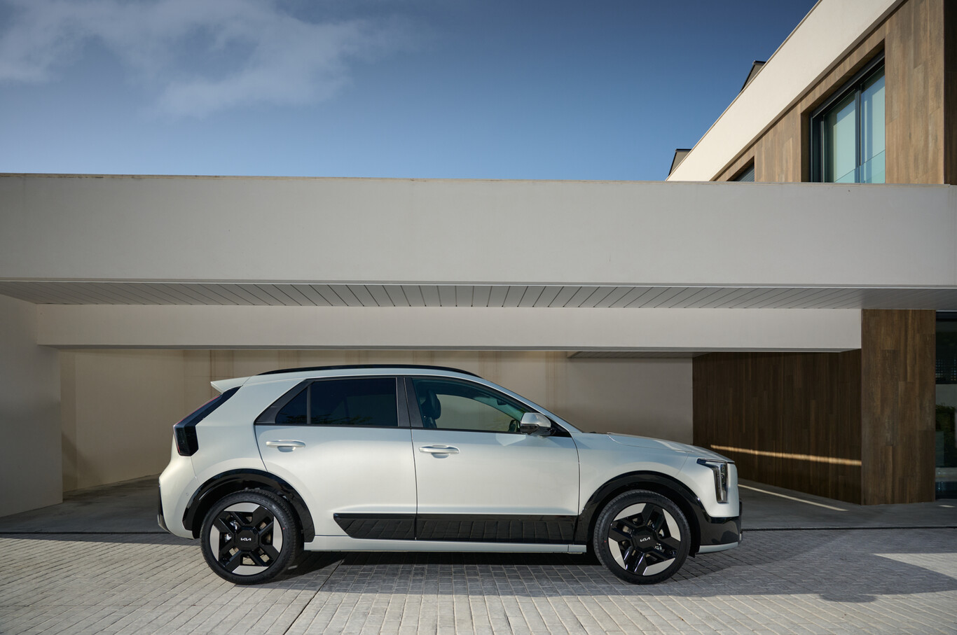 Kia Niro hybride blanc vu de profil devant une maison moderne