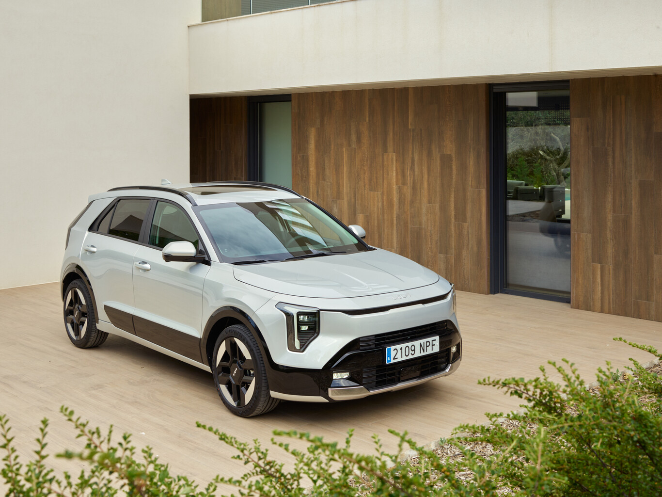 Kia Niro hybride blanc stationné devant une maison contemporaine