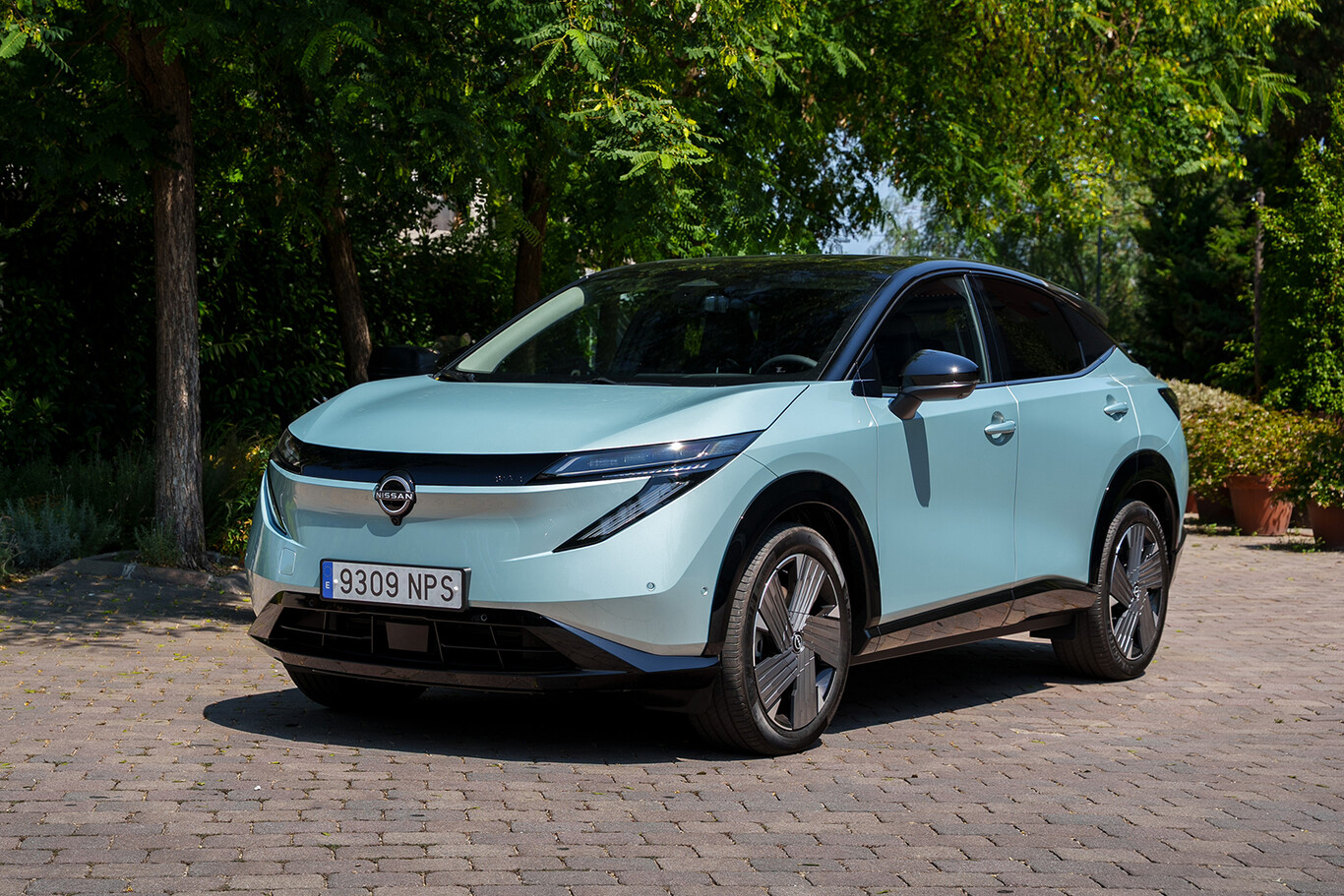 Nissan Ariya 2027 électrique bleu clair vu de trois quarts avant sous les arbres