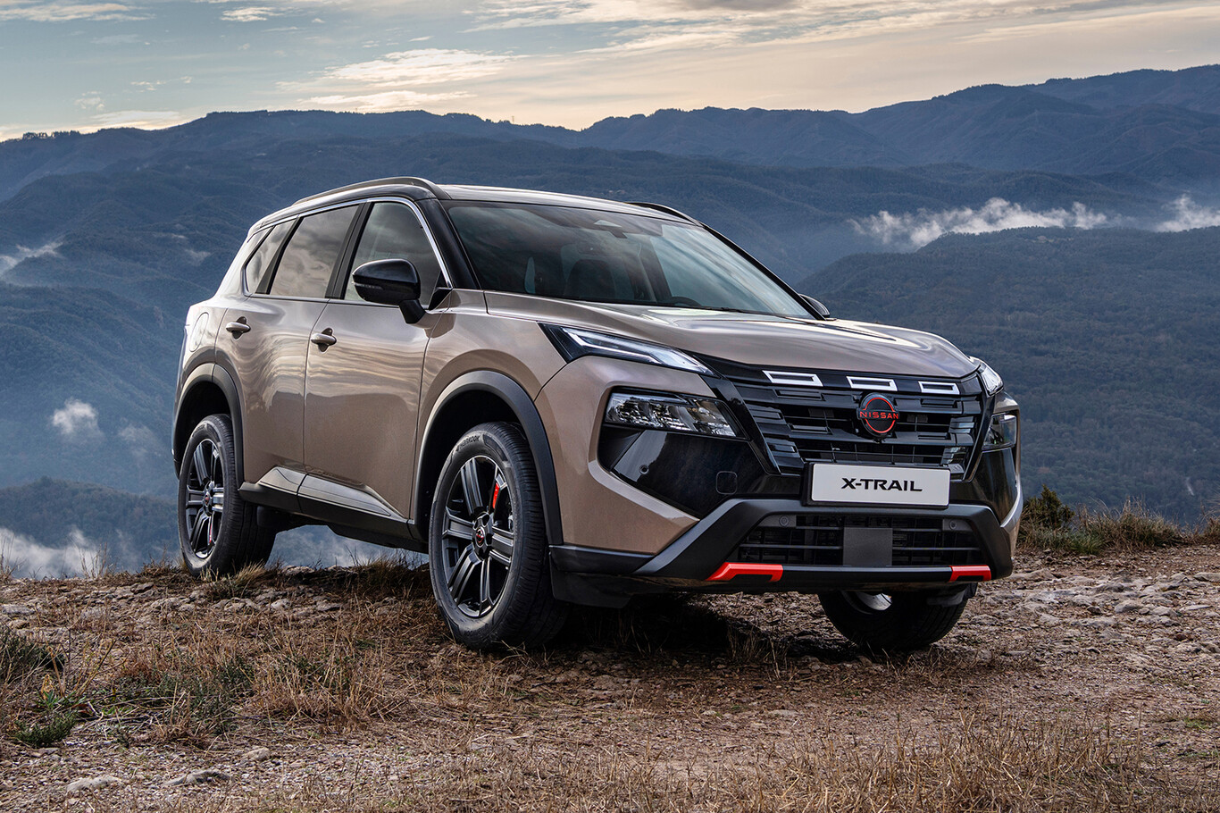 Nissan X-Trail N-Trek beige avec détails rouges photographié sur un terrain montagneux