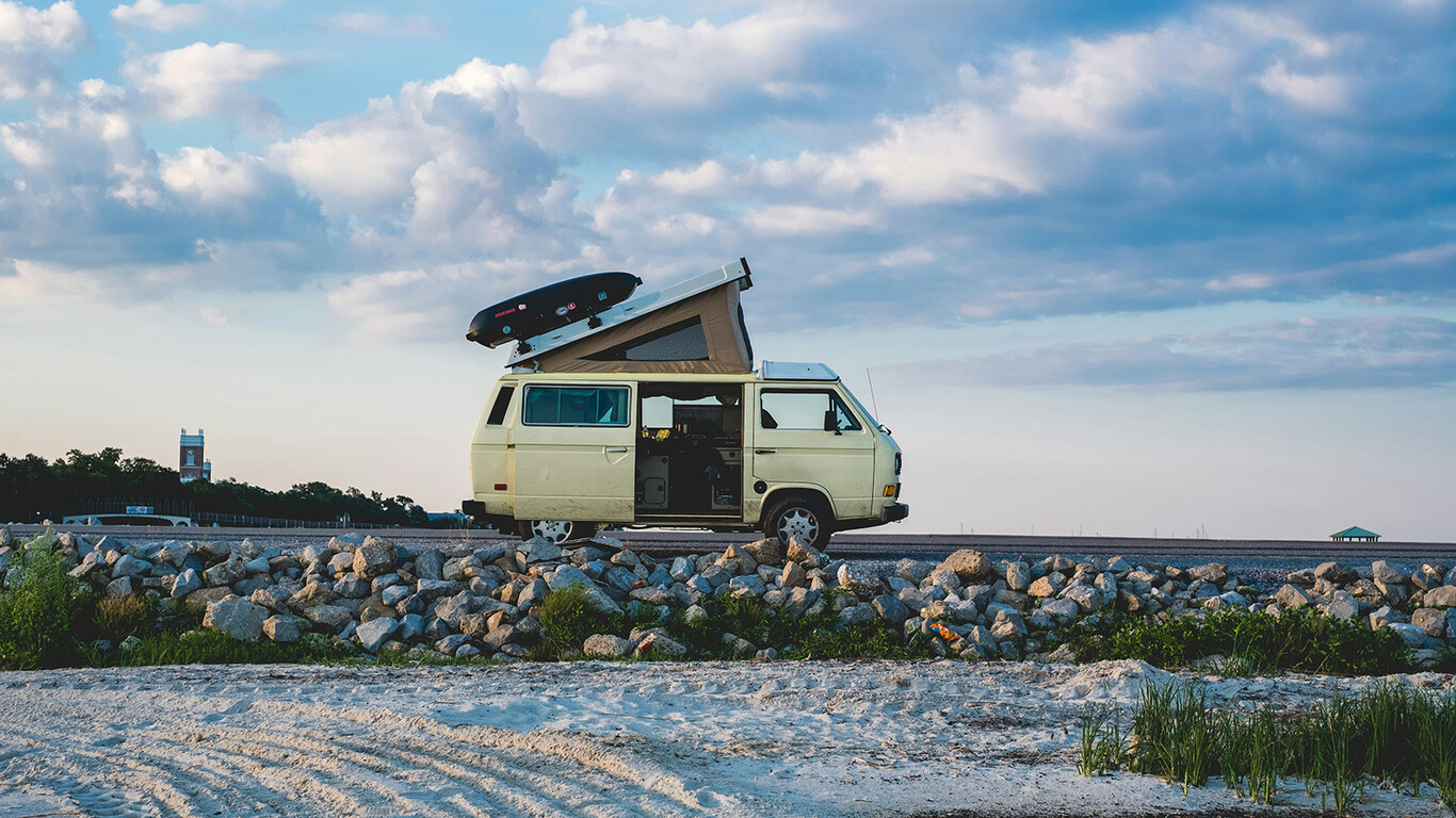 Volkswagen combi aménagé avec toit relevable près d'une plage