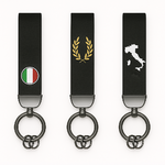 Trois porte-clés noirs alignés sur fond blanc, décorés d’un drapeau italien, d’une couronne dorée et de la carte de l’Italie